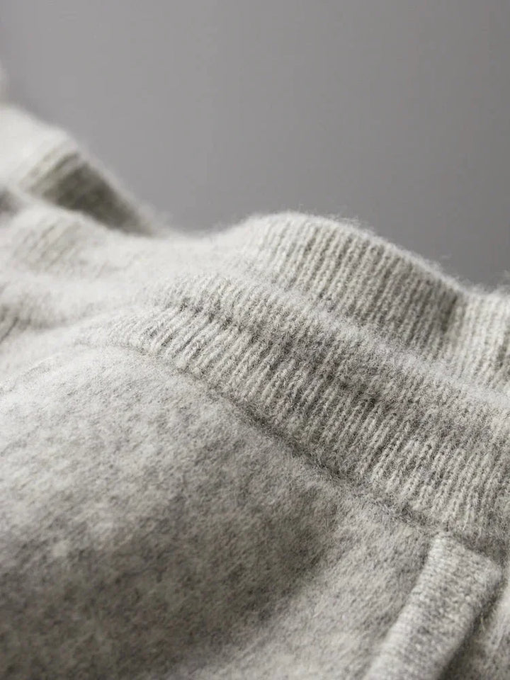Close-up of a soft, light gray knitted fabric with ribbed waistband and seam details, highlighting comfortable pants made from durable construction—ideal for cozy loungewear like Merino wool pants against a neutral background.