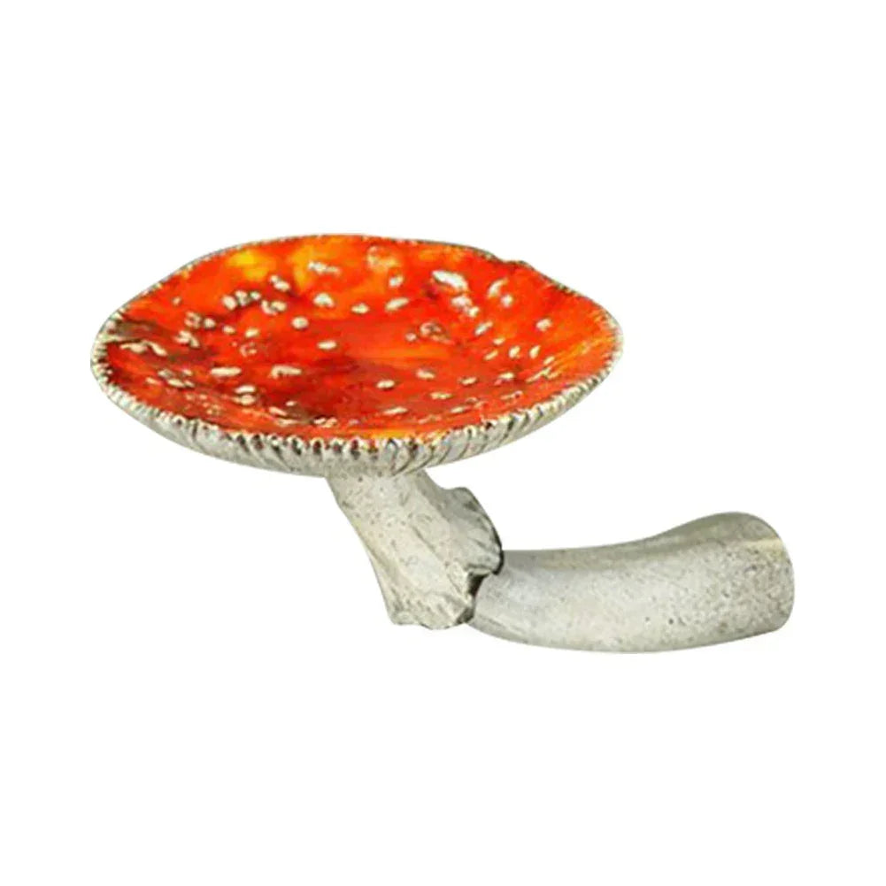 A ceramic object shaped like a red and white spotted mushroom cap with a short, curved, gray stem resembling a whimsical pipe—perfect as unique home decor. The background is plain white.