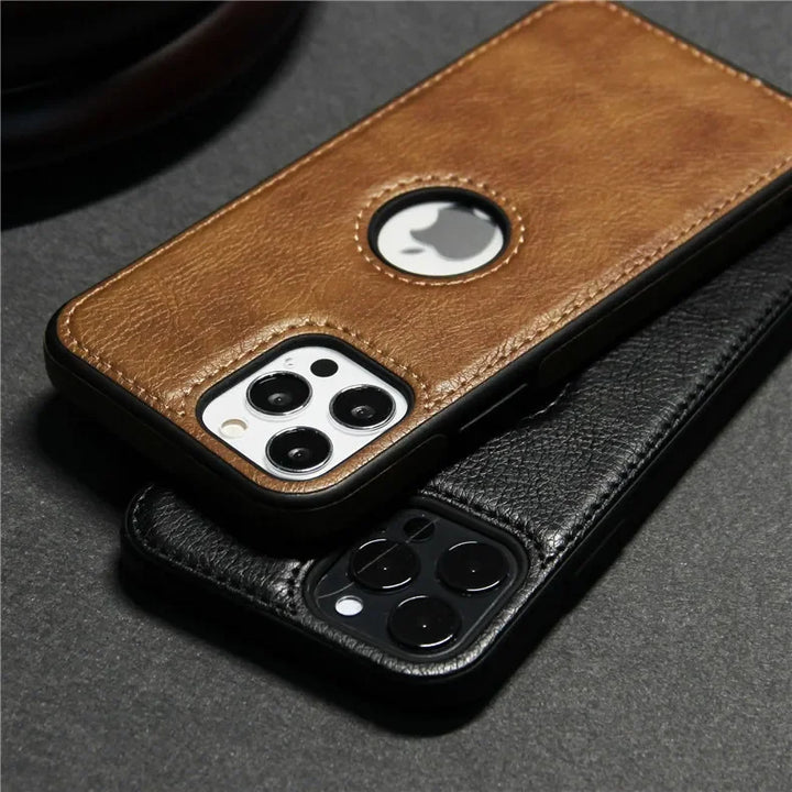 Two smartphones in slim protective cases, one brown and one black, rest on a dark surface. The brown luxury leather phone case has a circular cutout for the Apple logo. Both phones feature triple rear cameras and are wireless charging compatible.
