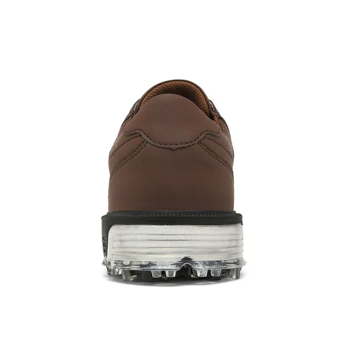 Rear view of a brown shoe with a black and white sole, featuring metal spikes and a high-traction outsole on the bottom, against a white background.
