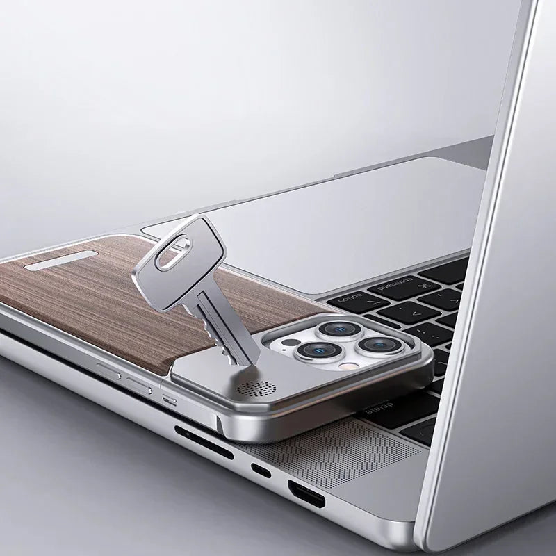 A key is inserted into a smartphone with a stylish phone case, partly tucked under a laptop, creating an illusion that the phone works like a USB drive. The devices are placed on a light gray surface.