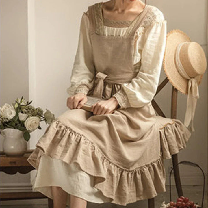 Woman in vintage beige linen dress with ruffles, sitting by flowers and straw hat, Rovelli