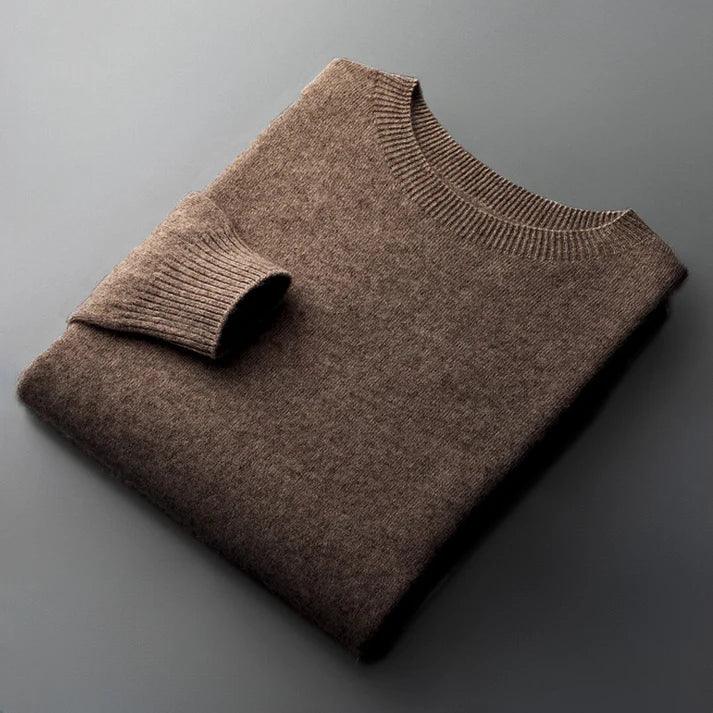 Folded brown wool sweater with ribbed collar and cuffs on gray surface, Rovelli clothing