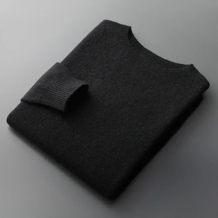 Folded black crew neck sweater on gray surface from Rovelli