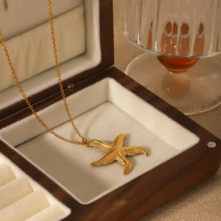 Gold starfish pendant necklace in a wooden jewelry box by Rovelli