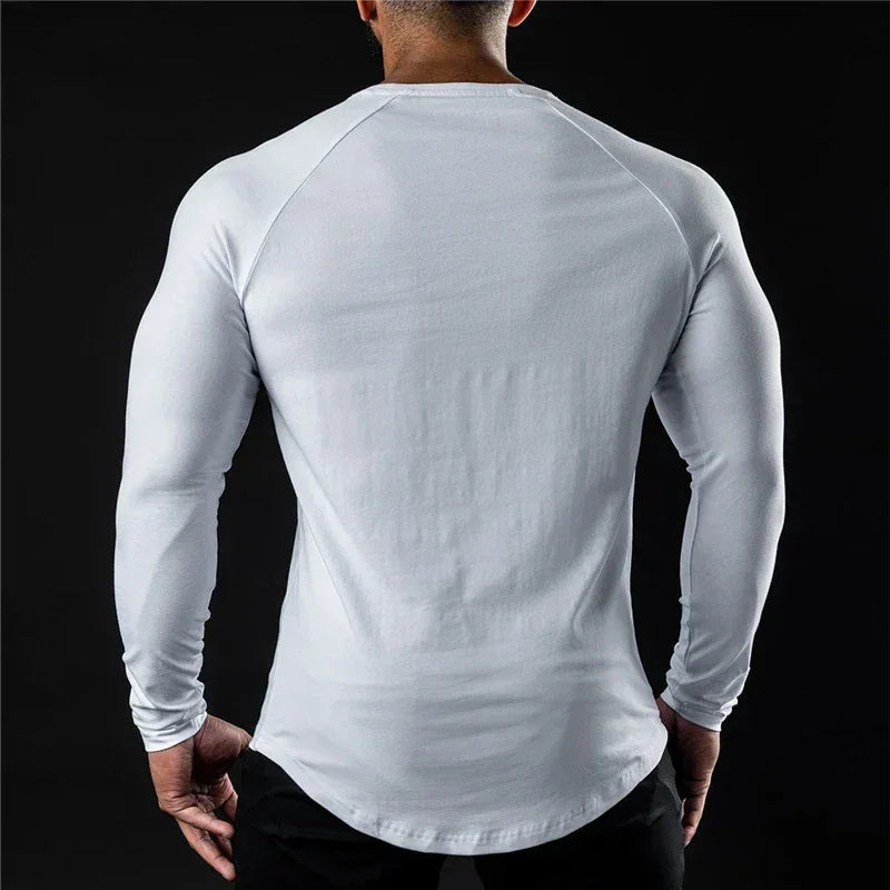 A person with a muscular build is shown from the back, wearing a fitted, moisture-wicking long sleeve shirt and black pants, standing against a black background.