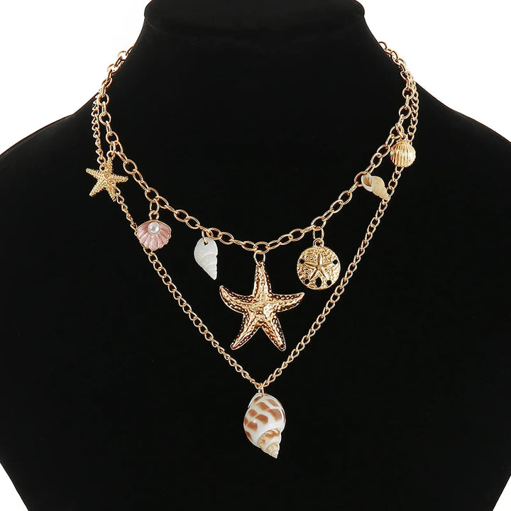 Gold layered necklace with starfish, shell, and sea-inspired charms on black display, Rovelli