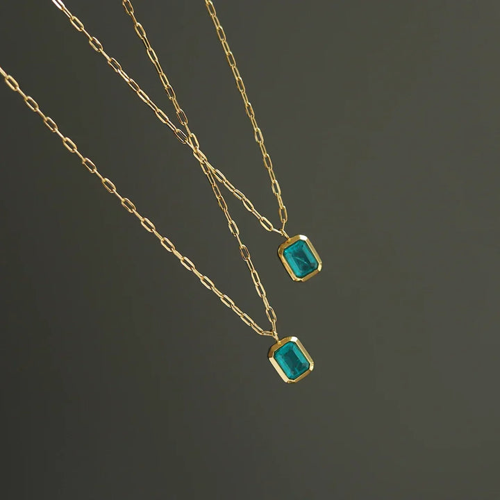 Two delicate 18K gold plated chains with rectangular green zirconia pendants are displayed against a plain dark background.