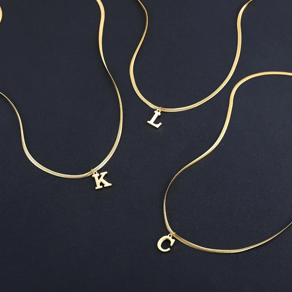 Gold initial necklaces with K, L, and C letter charms on black background, Rovelli jewelry