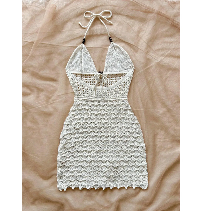 White crochet halter dress with tie front, beachwear style, displayed on beige fabric, Rovelli