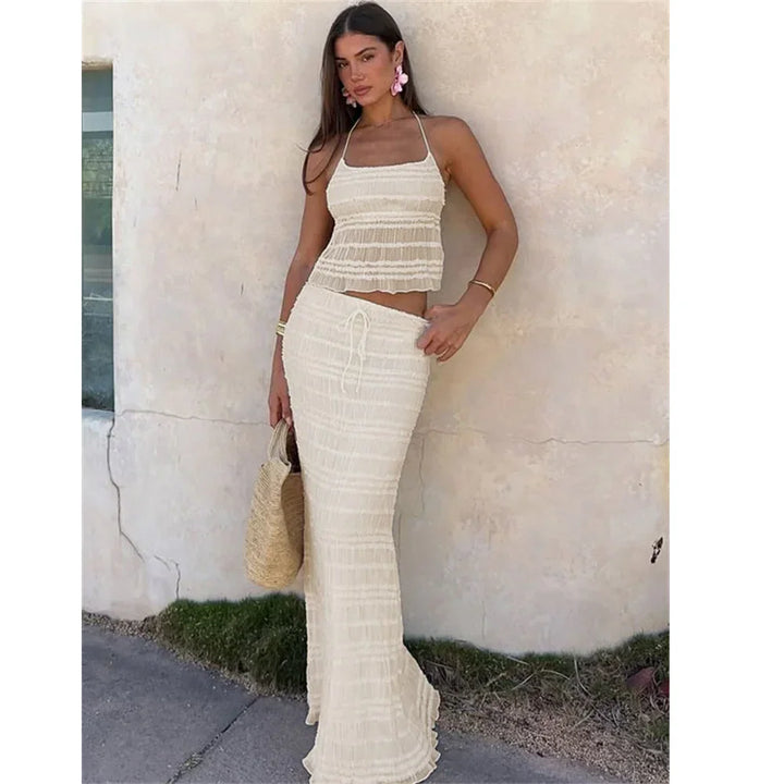 Woman wearing beige two-piece summer outfit with maxi skirt, straw bag, Rovelli fashion