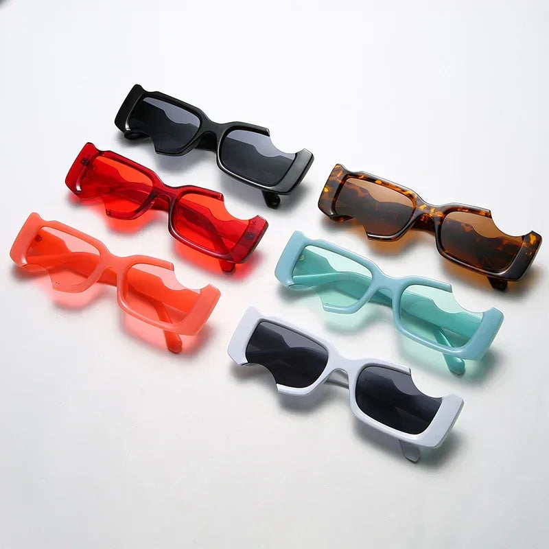Six pairs of avant-garde sunglasses in rectangular shapes—black, red, tortoiseshell, coral, mint green, and light blue—are arranged on a white surface. Each pair offers stylish UV400 protection for your eyes.