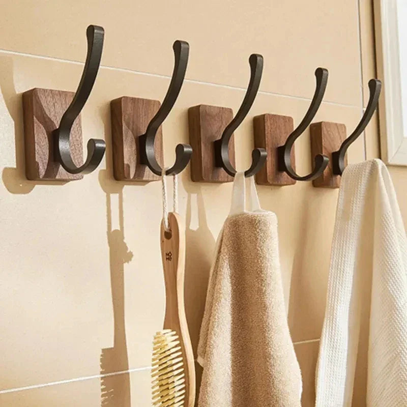 Set of modern wooden wall hooks holding towels and a brush, bathroom storage by Rovelli