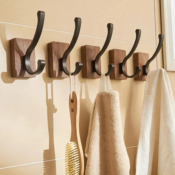 Set of modern wooden wall hooks holding towels and a brush, bathroom storage by Rovelli
