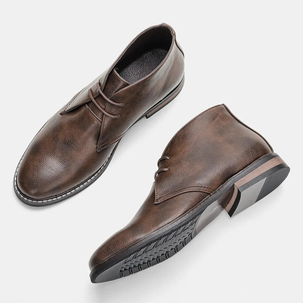 A pair of brown After-Ride Chukka leather boots with laces, shown on a white background. One boot stands upright, displaying the top and side, while the other lies on its side to reveal the sole’s tread pattern.