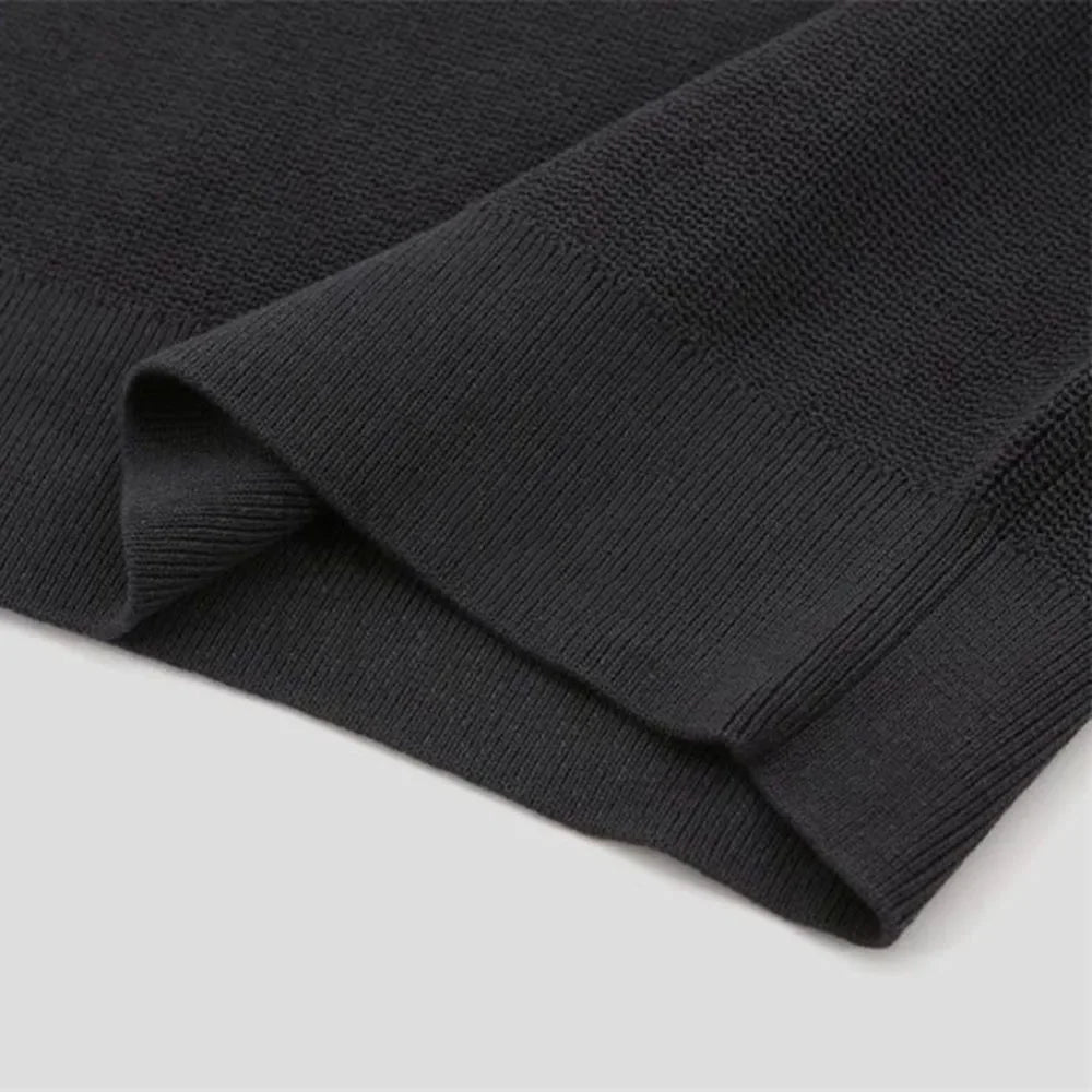 A black quarter zip polo sweater with ribbed detailing, set against a white background.