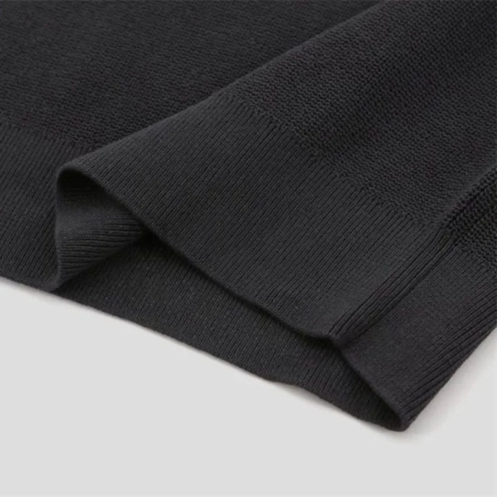 A black quarter zip polo sweater with ribbed detailing, set against a white background.