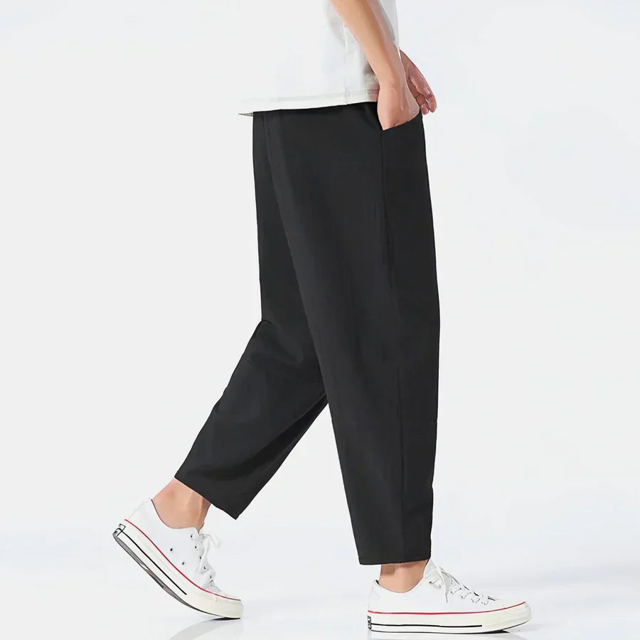 Rovelli relaxed fit black trousers with white sneakers, side view on white background