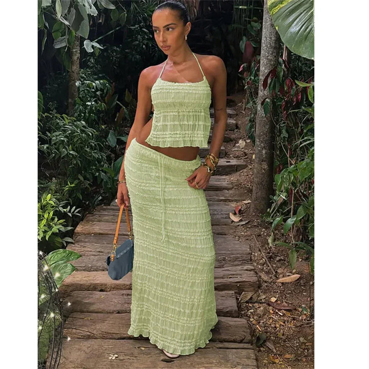 Woman in light green two-piece summer outfit on a wooden garden path, Rovelli fashion