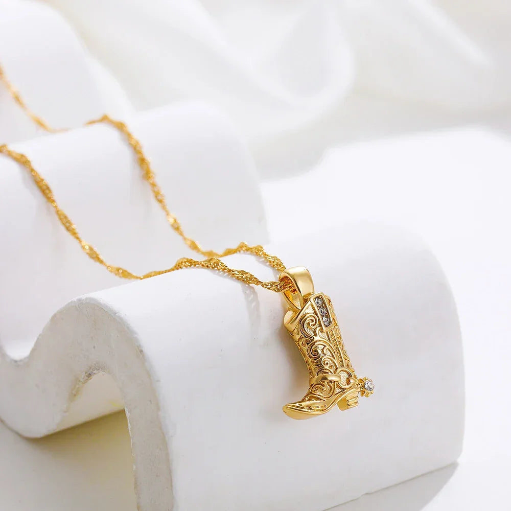Gold cowboy boot pendant necklace with intricate design, Rovelli jewelry on white background