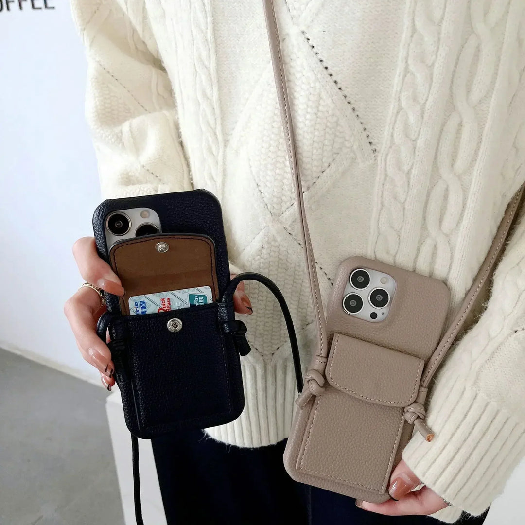 A person wearing a cream cable-knit sweater holds two leather phone cases with detachable lanyards—one black, one beige. The black card holder case has cards inside, while both cases securely hold smartphones.