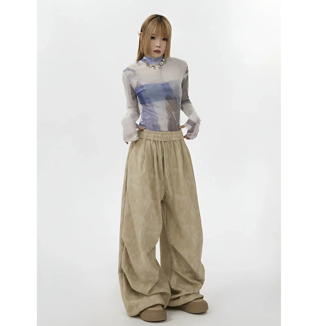 Model wearing sheer printed top and oversized beige pants, Rovelli fashion photography