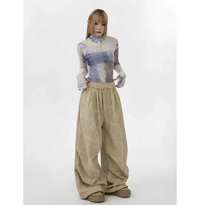 Model wearing sheer printed top and oversized beige pants, Rovelli fashion photography