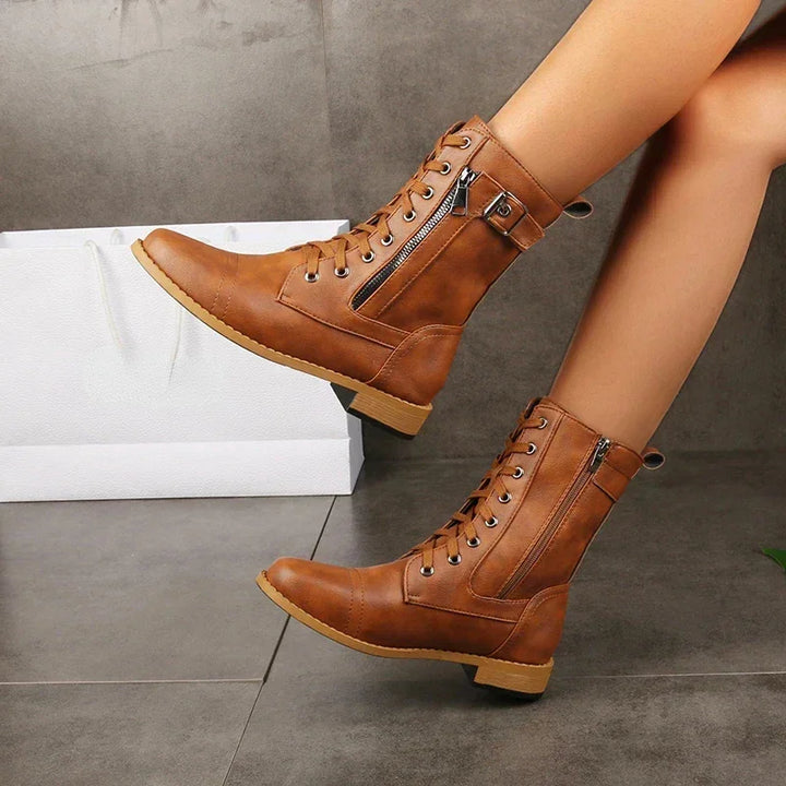Rovelli tan lace-up combat boots with zippers, worn indoors, modern tile background