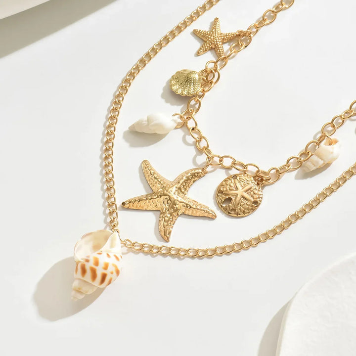 Gold necklace with starfish, shell, and seashell charms, beach jewelry by Rovelli