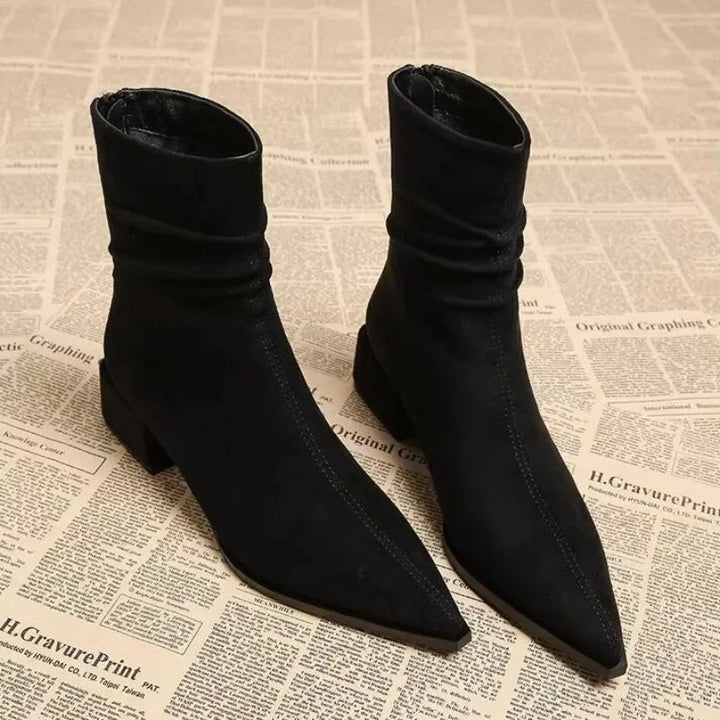 Rovelli black pointed toe ankle boots with block heels on newspaper background