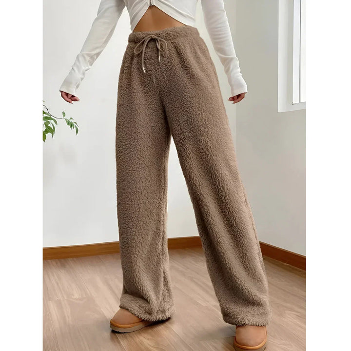 Woman wearing brown fleece jogger pants from Rovelli, cozy indoor setting, wood floor