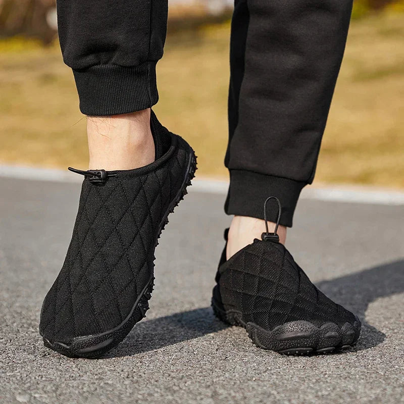 Person wearing black quilted slip-on sneakers from Rovelli, standing on outdoor pavement