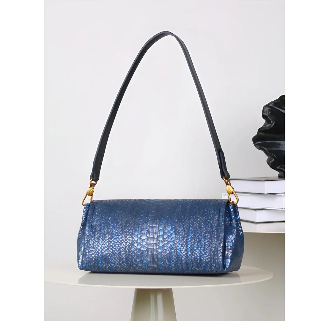 Rovelli blue textured shoulder bag with gold hardware on round table, modern decor