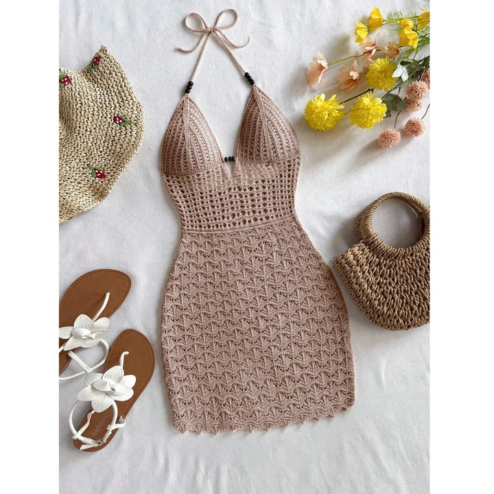 Beige crochet halter dress with straw hat, woven bag, sandals, and flowers flat lay