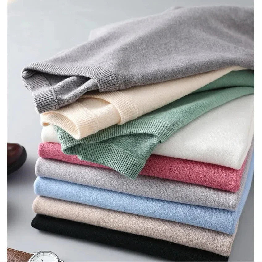 Stack of folded Rovelli sweaters in assorted colors on a gray surface