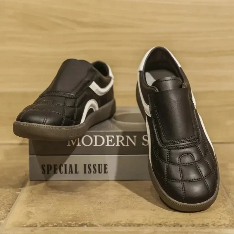 Rovelli black slip-on sneakers with white accents on display box, modern stylish shoes