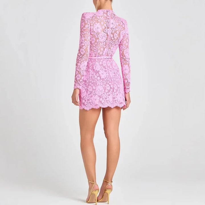Back view of woman wearing pink lace mini dress with long sleeves and gold heels, Rovelli fashion.