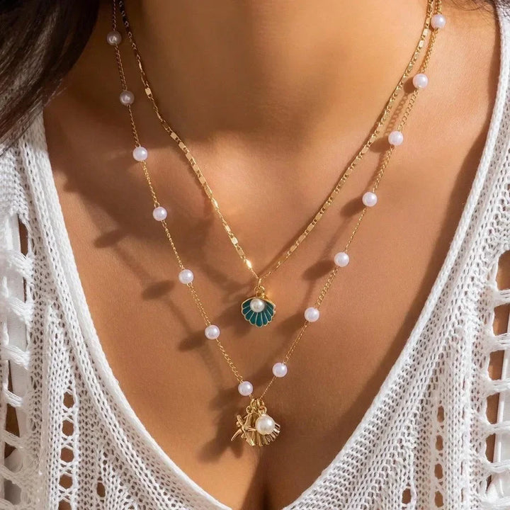 Woman wearing layered gold and pearl shell necklaces by Rovelli, close-up on chest