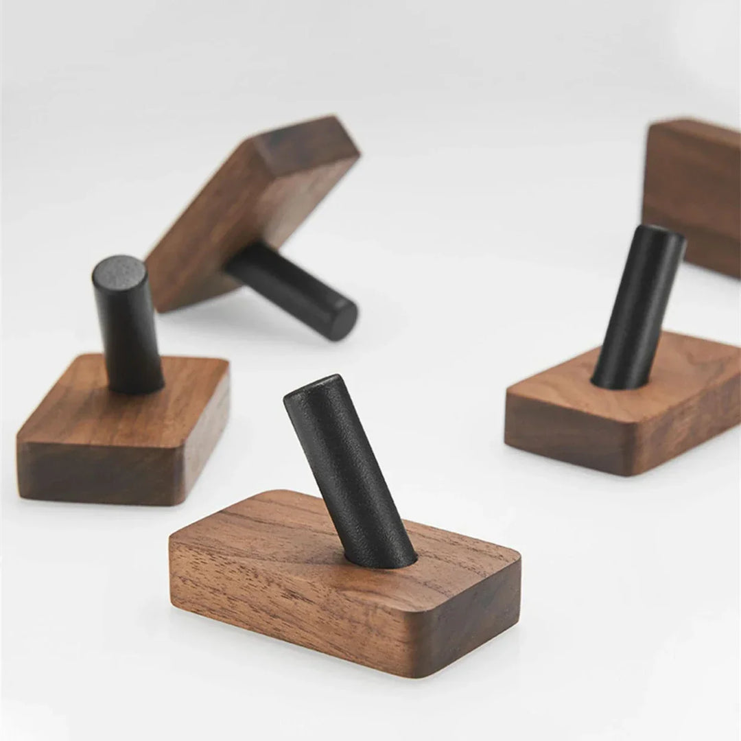 Minimalist Rovelli wooden wall hooks with black metal pegs on a white background.