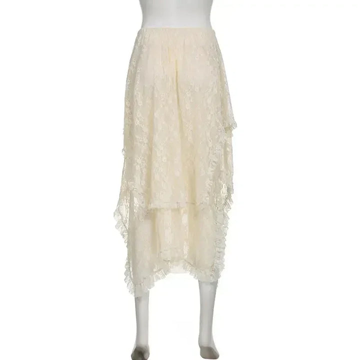 A cream-colored, high-waisted lace skirt with an asymmetrical hemline is displayed on a mannequin. The skirt features delicate floral lace detailing and layered, uneven edges for a romantic look.
