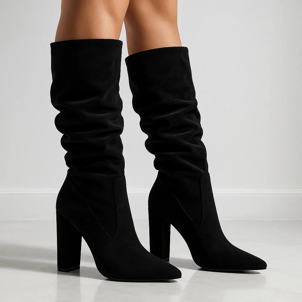 Black suede slouchy heeled boots by Rovelli on a light background
