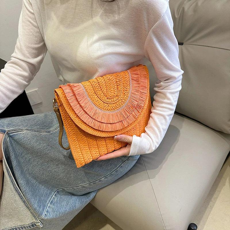 Woman holding an orange woven clutch bag on sofa, Rovelli accessories fashion