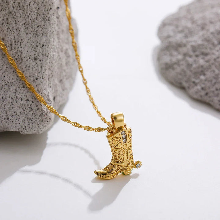 Rovelli gold cowboy boot pendant necklace with intricate design, styled on stone background