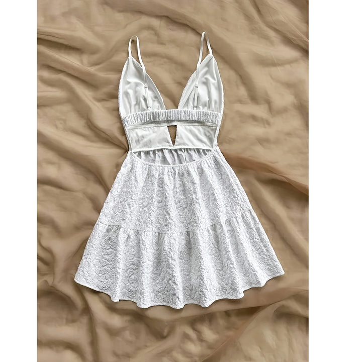 White lace mini dress with deep V-neck and spaghetti straps by Rovelli on beige fabric