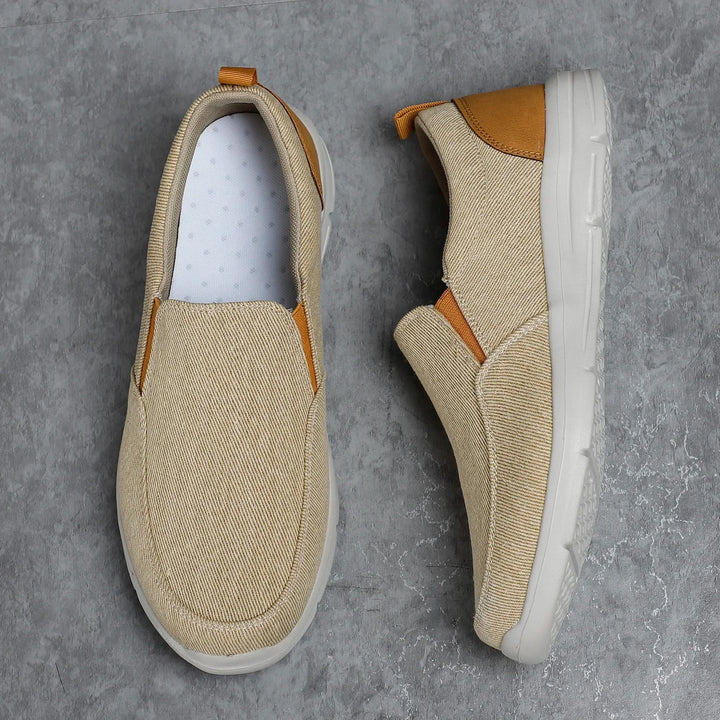 Rovelli beige slip-on canvas shoes with tan accents on gray textured background