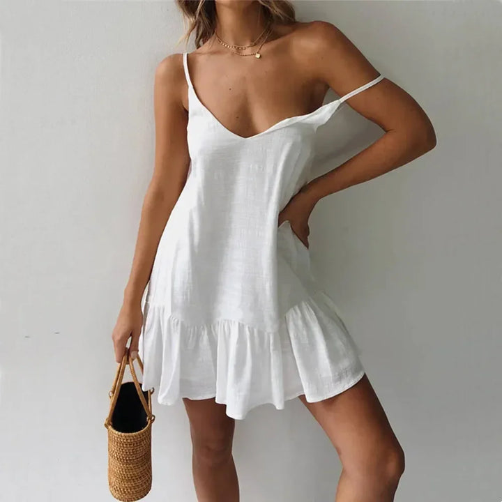 Woman wearing white summer dress with ruffle hem, holding woven straw bag, Rovelli fashion