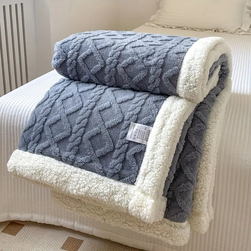 Rovelli gray sherpa fleece blanket with diamond pattern and white trim on a bed