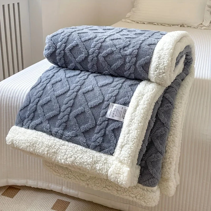 Rovelli gray sherpa fleece blanket with diamond pattern and white trim on a bed