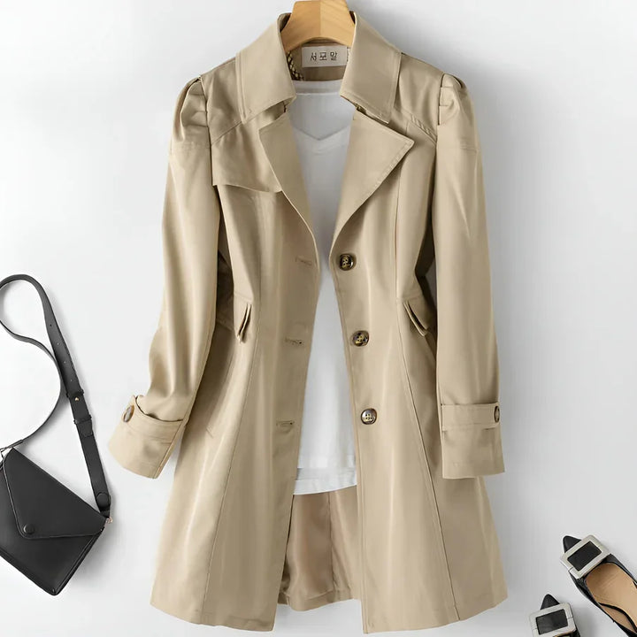 Beige trench coat with white top, black crossbody bag, and black buckle heels from Rovelli