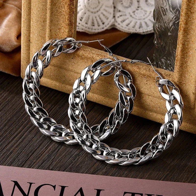 Rovelli silver twisted hoop earrings on dark wood with lace and frame backdrop